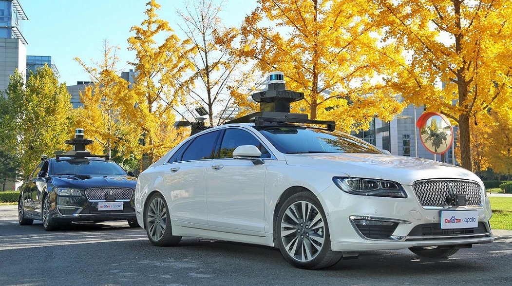 Autonomous vehicle testing on urban street with fall foliage.